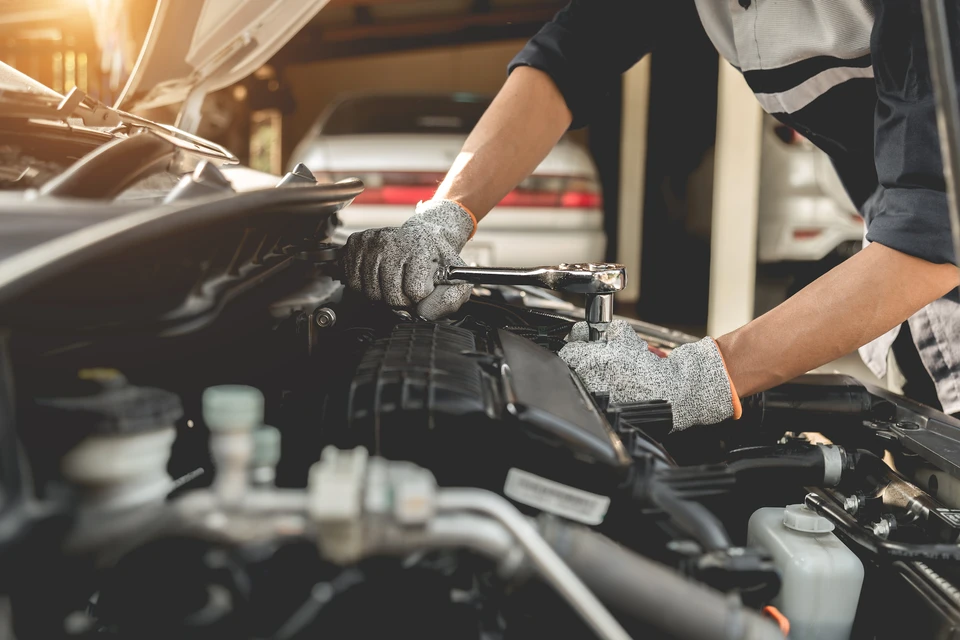 Mécanicien automobile travaillant sous le capot ouvert d'un véhicule dans un garage professionnel