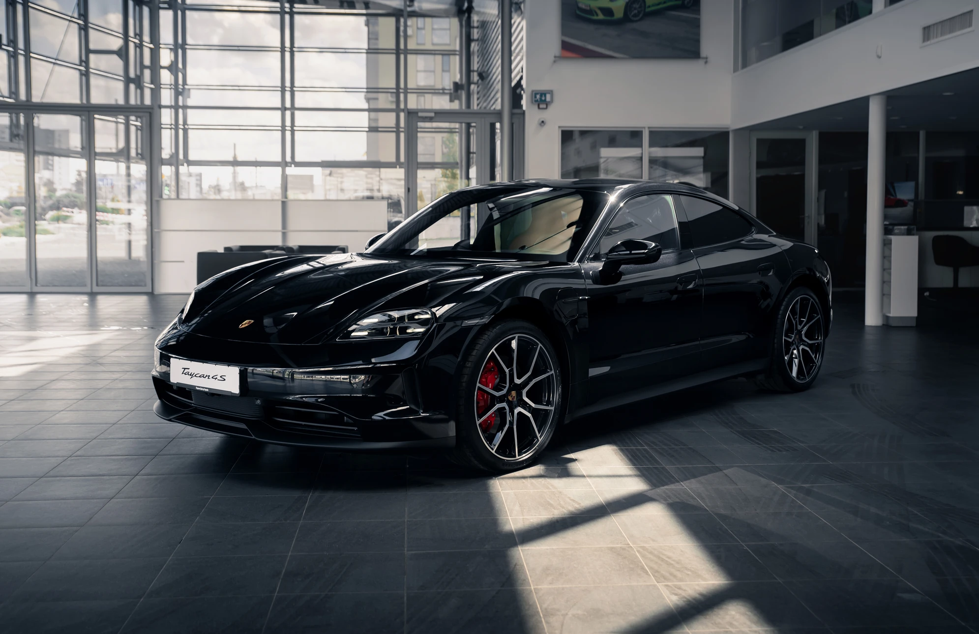 Showroom automobile moderne avec voiture électrique Porsche Taycan noire stationnée sur carrelage gris