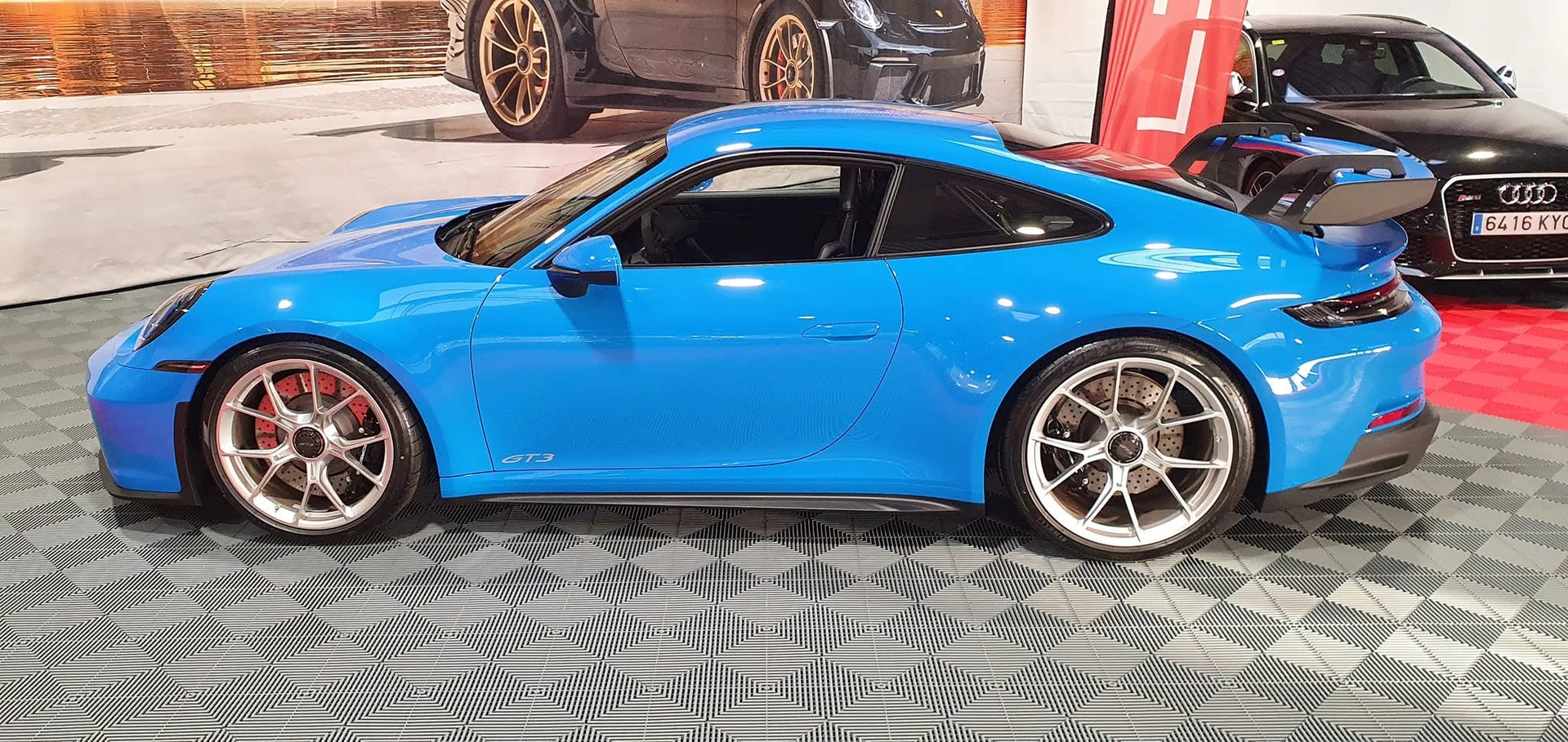 Intérieur véhicule automobile, technicien en combinaison bleue utilise tablette diagnostique connectée par câbles au système électronique