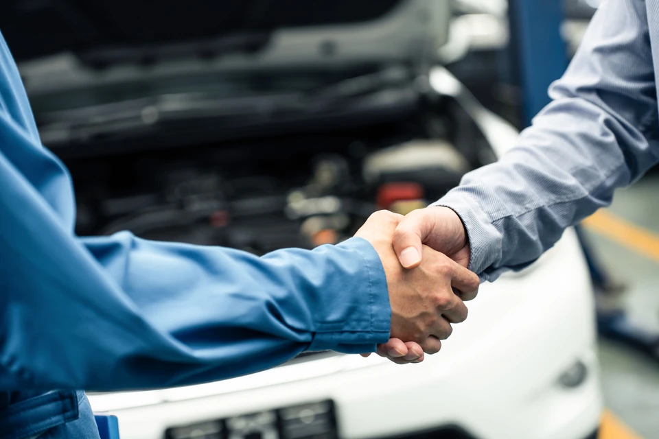 Mécanicien automobile effectuant une maintenance moteur, mains gantées manipulant un filtre à huile cylindrique neuf près du compartiment moteur ouvert