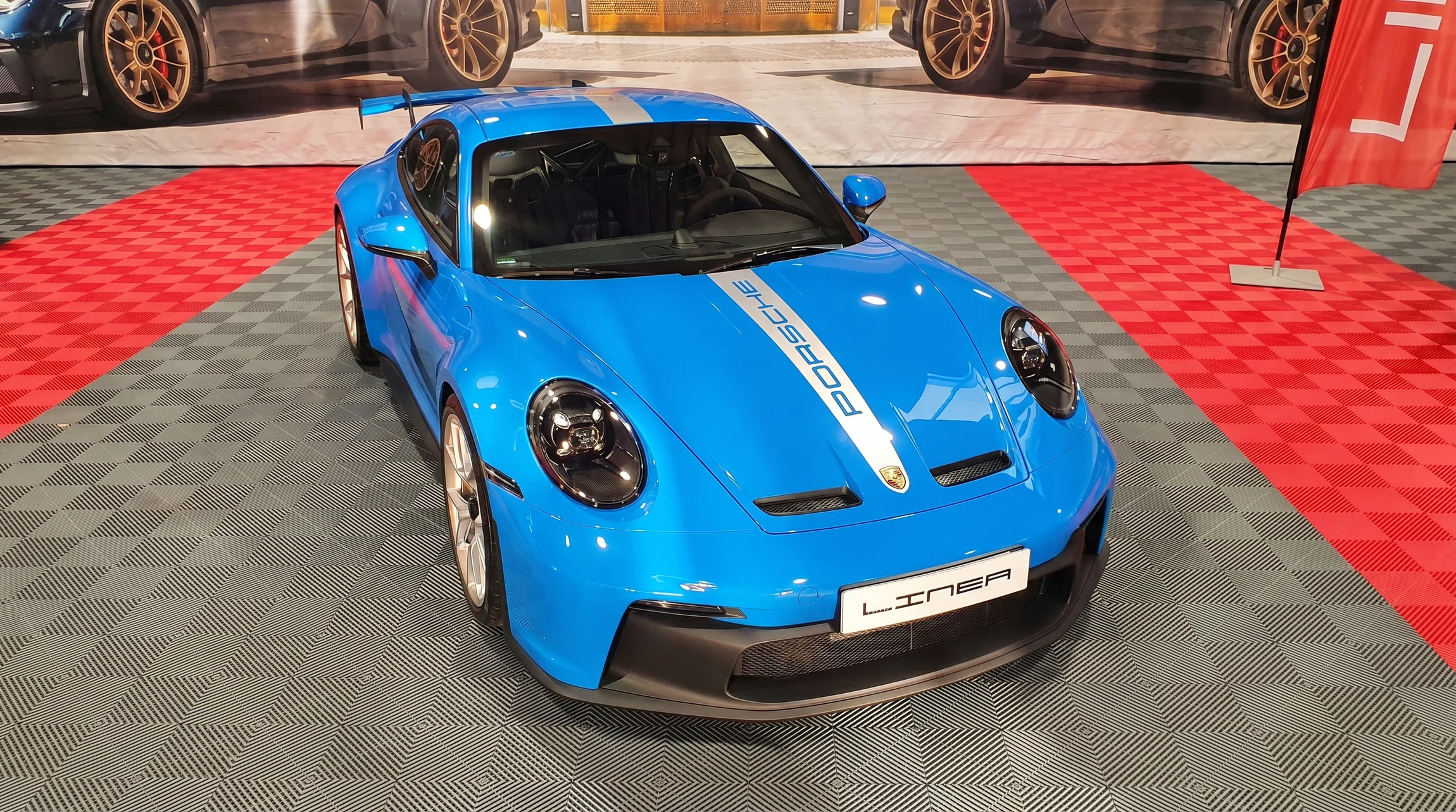 Showroom automobile moderne avec voiture électrique Porsche Taycan noire stationnée sur carrelage gris